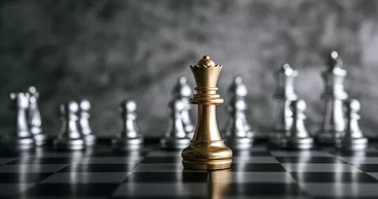 imagem de peças de xadrez prata sobre um tabuleiro, com uma peça em ouro na frente em destaque, representando a importância do posicionamento estratégico