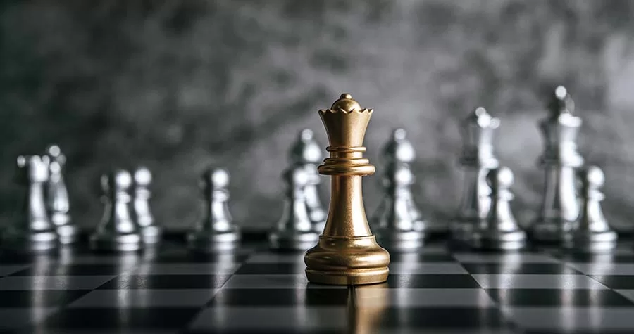 imagem de peças de xadrez prata sobre um tabuleiro, com uma peça em ouro na frente em destaque, representando a importância do posicionamento estratégico